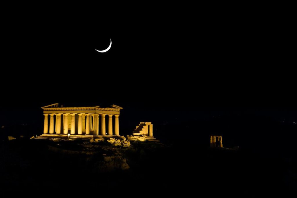 A moonlit night over the ancient Greek temples of Agrigento, Sicily. A dramatic landscape bathed in the soft glow of the crescent moon, with the towering columns and ruins of the Valley of the Temples rising majestically against the inky black sky. The serene, otherworldly atmosphere is accentuated by the long shadows cast by the temples, creating a sense of timeless wonder. The cool, crisp air and the sound of the gentle breeze rustling through the olive trees add to the tranquil, contemplative mood. The composition features the foreground with the detailed architecture of the temples, the middle ground with the rolling hills and olive groves, and the distant horizon blending into the star-studded night sky. A dreamy, enchanting scene that captures the essence of this UNESCO World Heritage site in its most serene and captivating state.